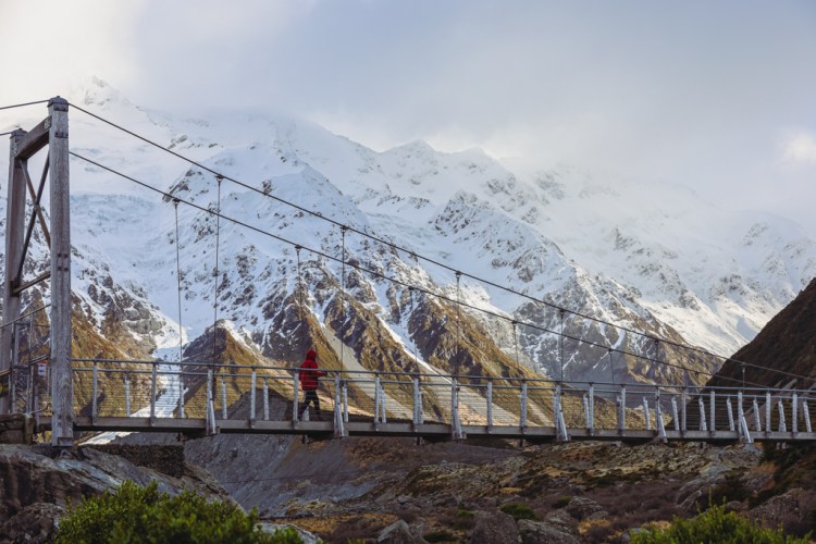 hiker walking across bridge in the mountains
