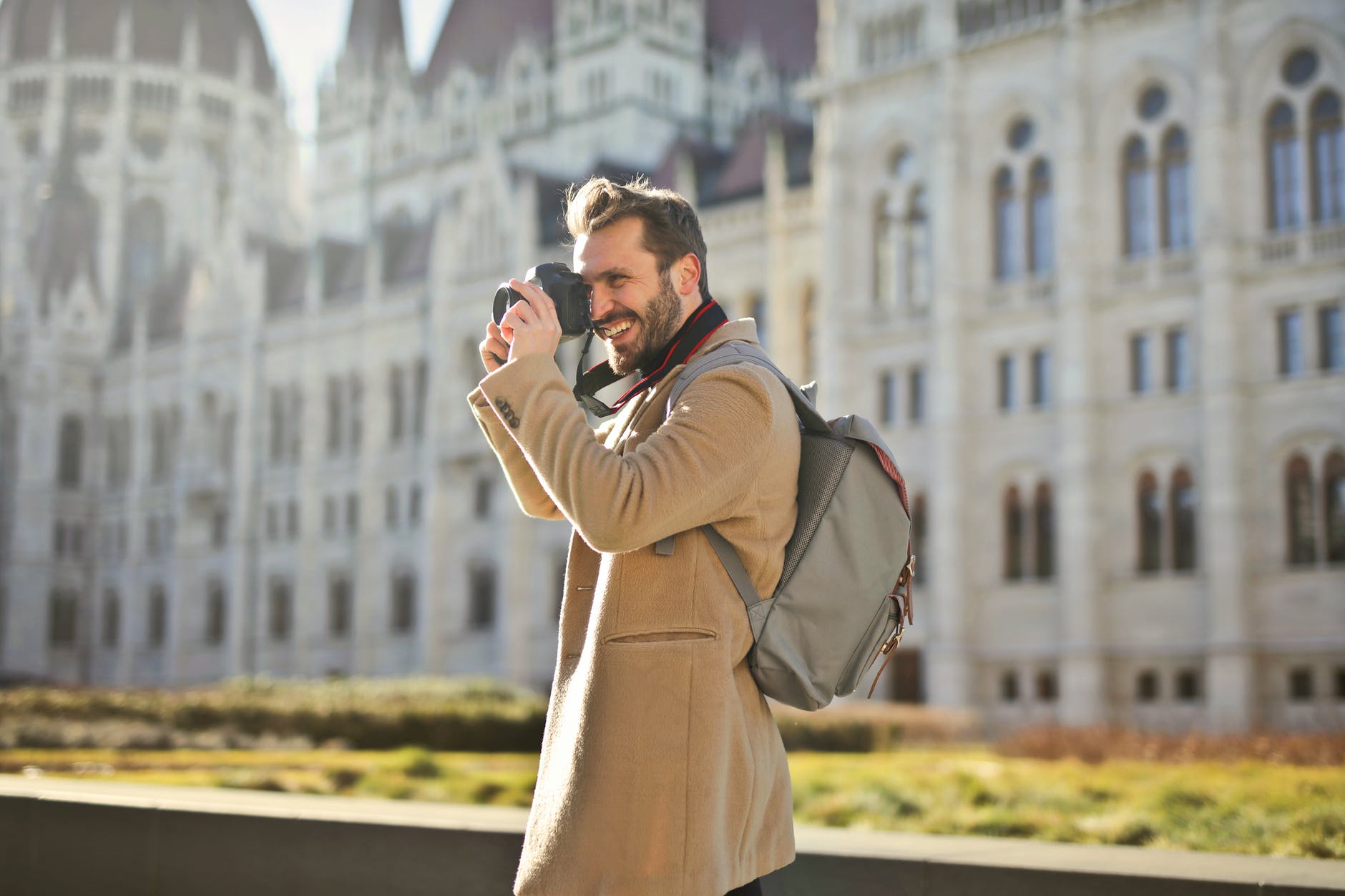 man wearing backpack holding and capturing images around him