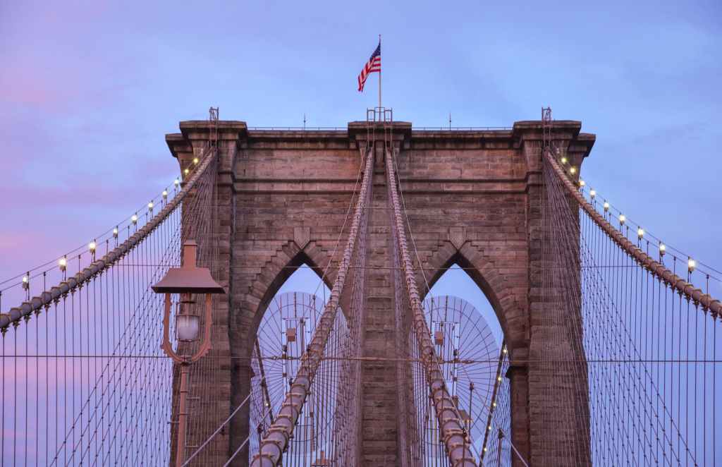 brown bridge leading photo with usa flag on top under blue sky
