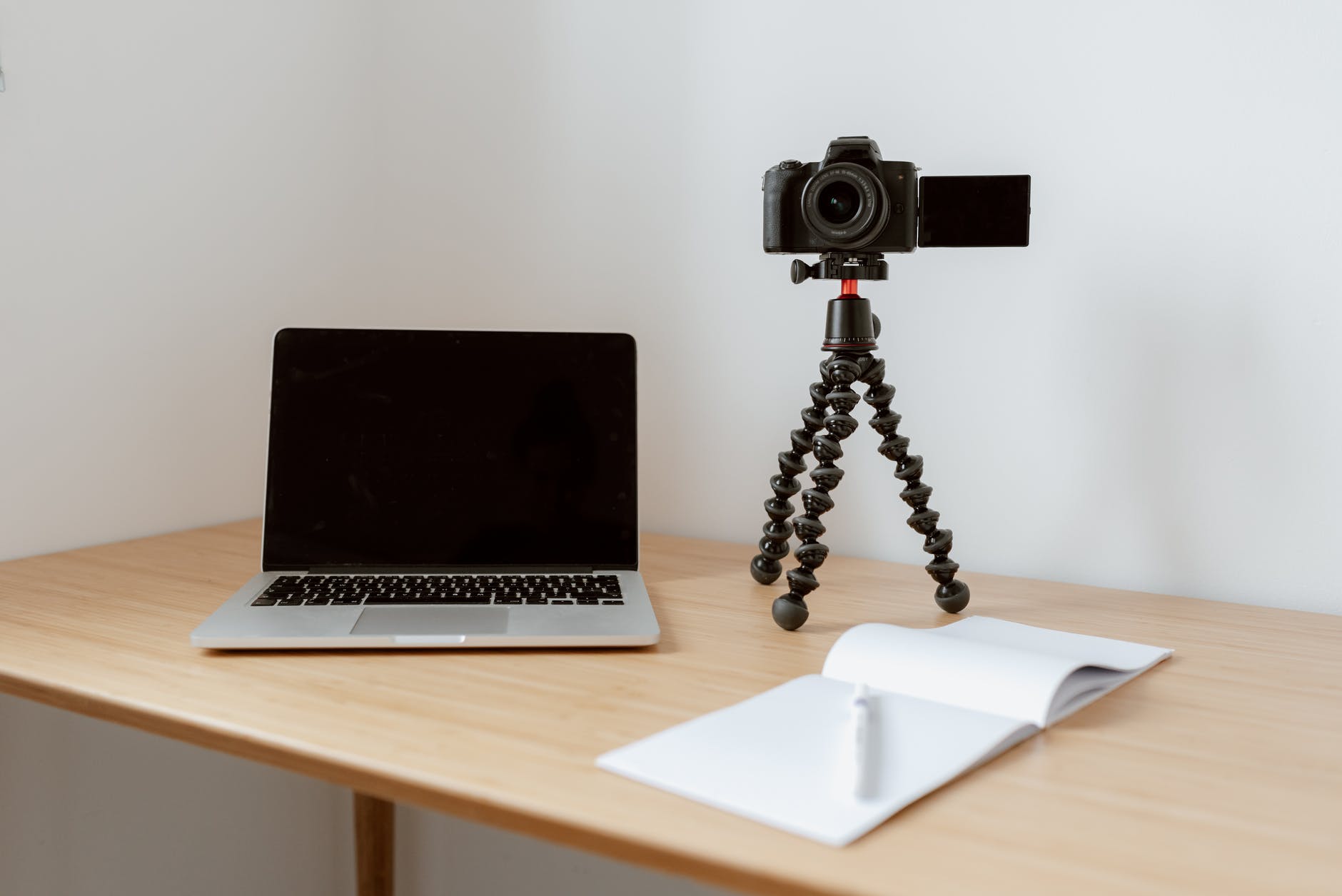 modern video camera on a mini gorilla tripod and laptop near opened notebook