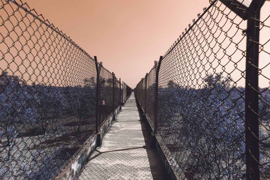 leading lines photography concrete footbridge with black chain link fences