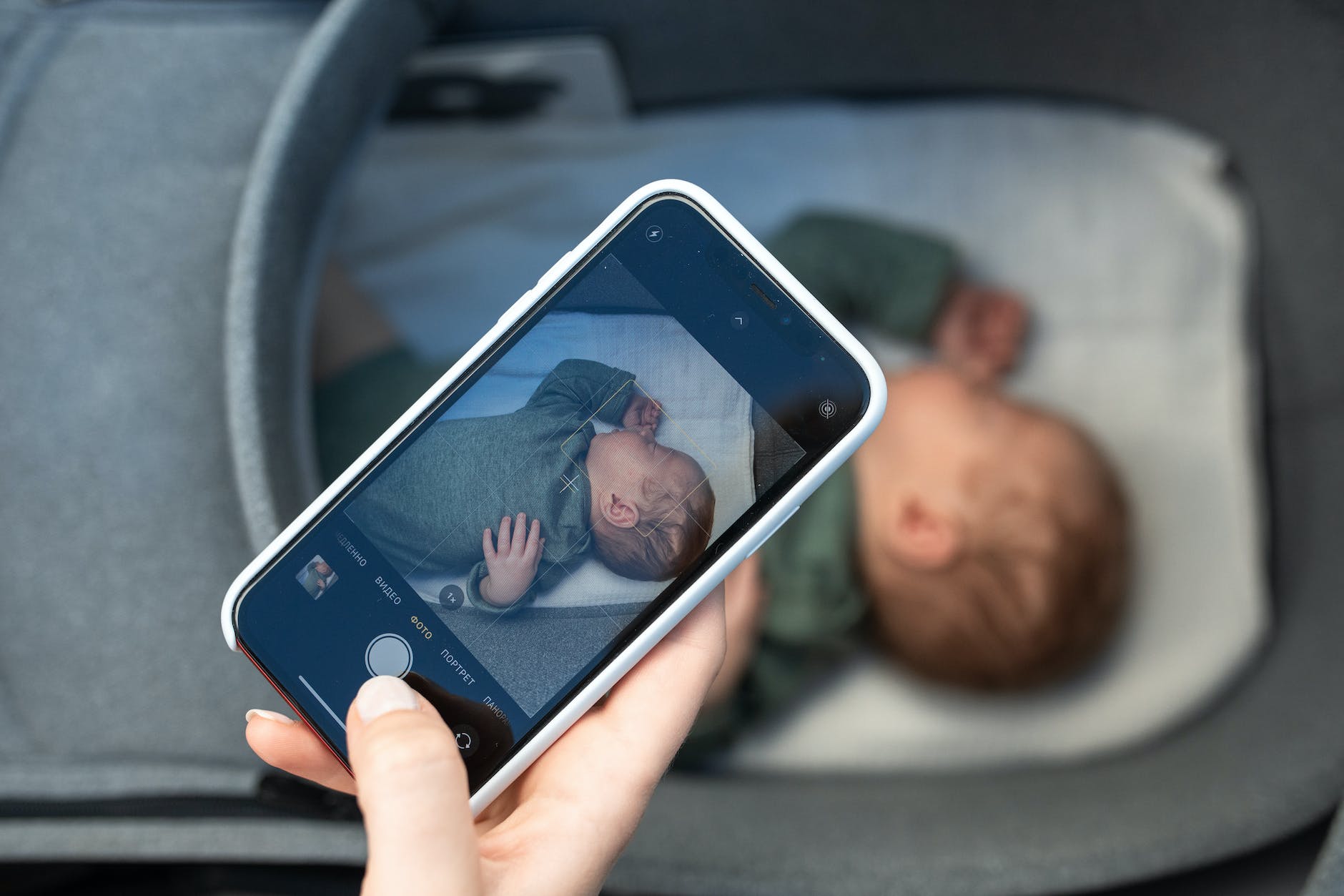 woman taking a photo of her newborn baby on a smartphone