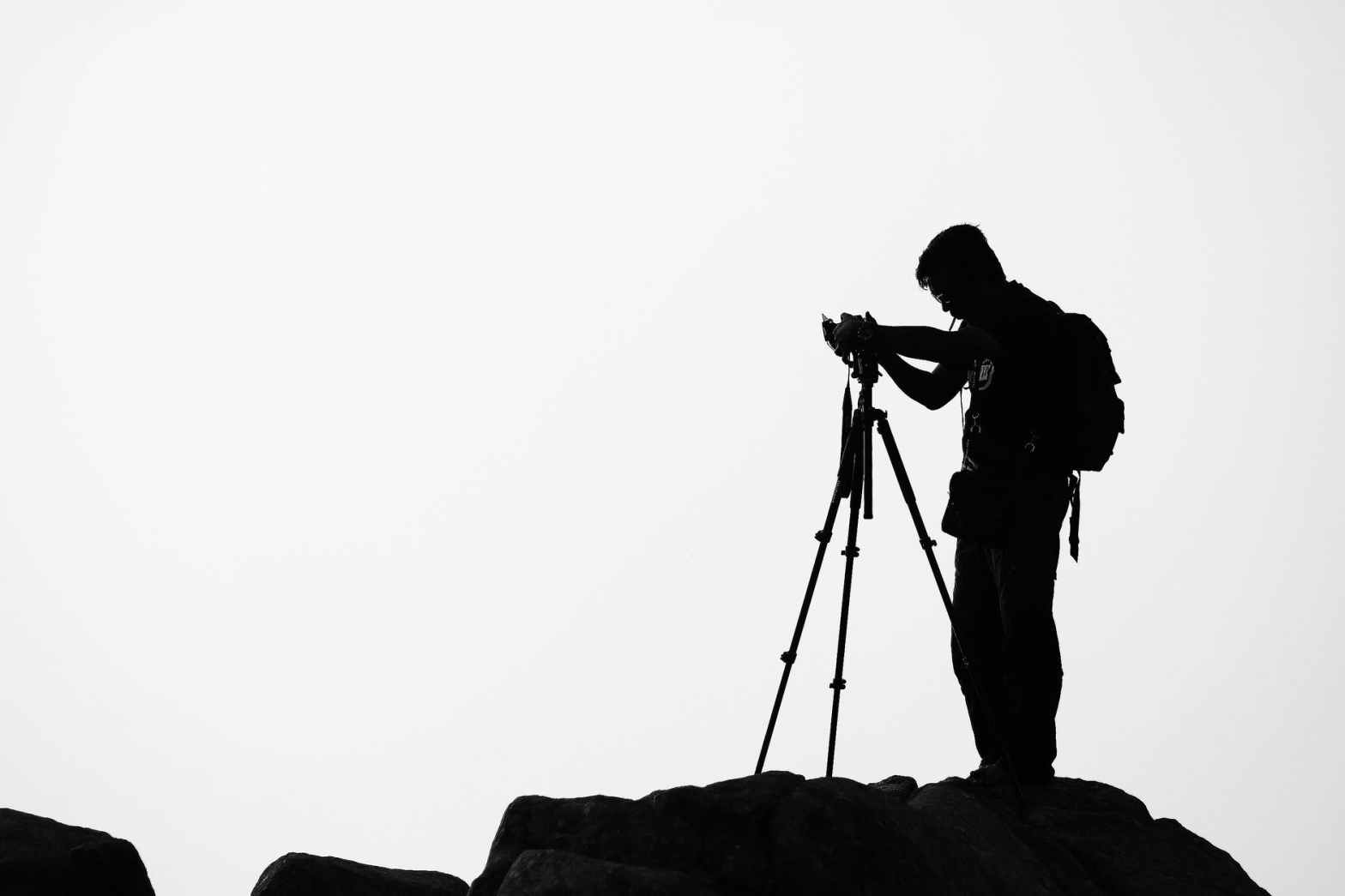 silhouette of man using tripod for photography